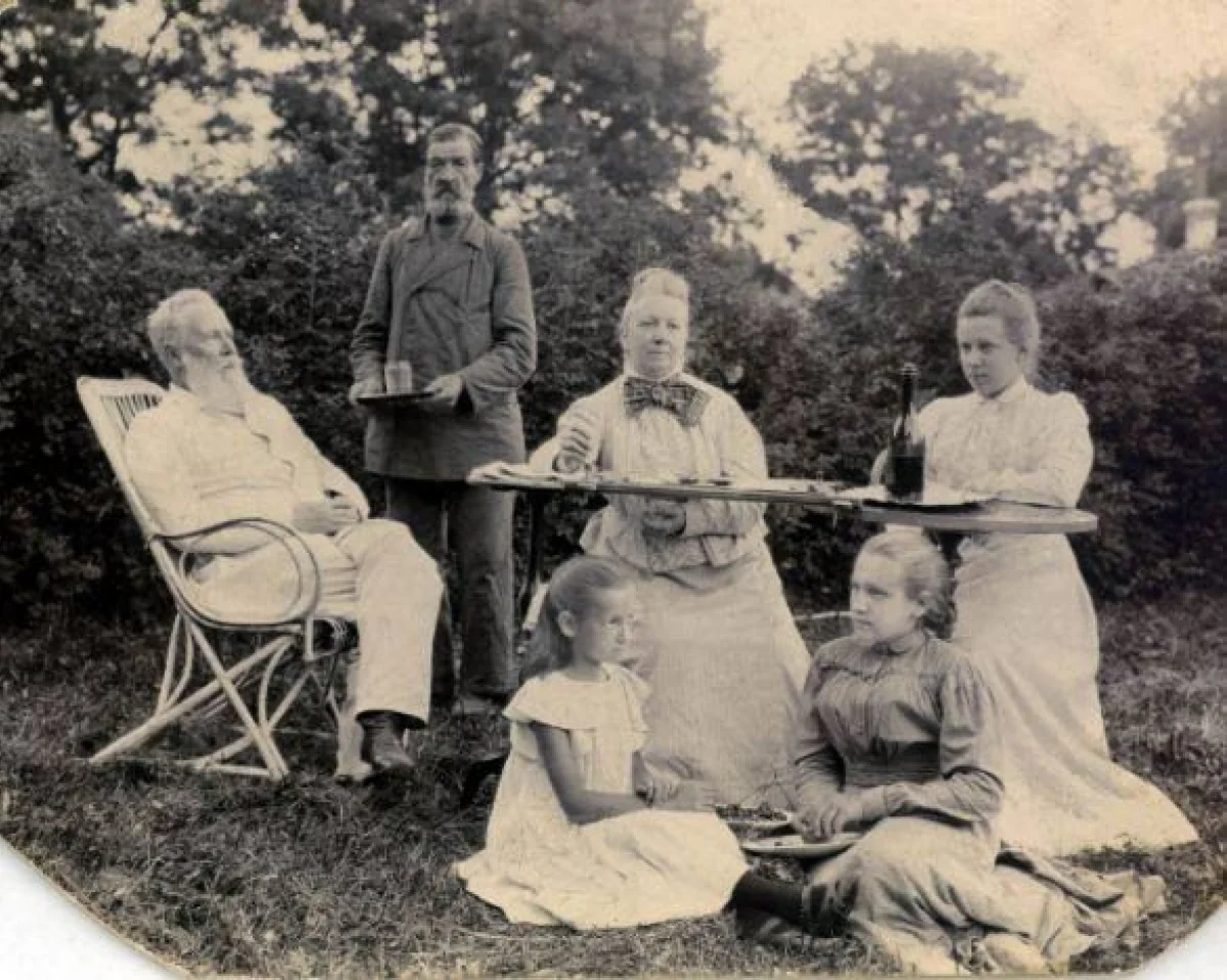 Фото из архива Ольги Боголеповой. Жуков с семьей. Жена и дочь сидят за столом. Слуга стоит с чашкой чая..  Кто на траве - не известно.